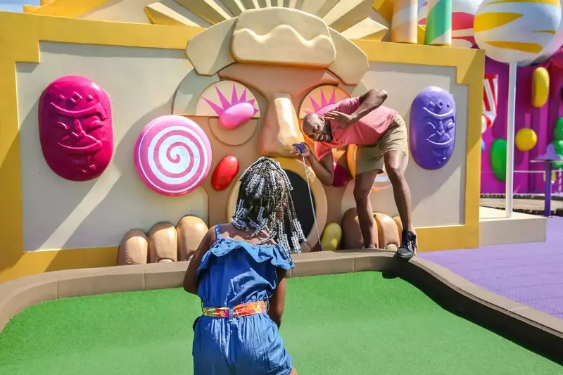 father and daughter playing on rooftop mini golf course